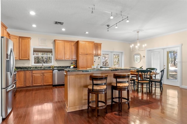 kitchen with pendant lighting, a center island, stainless steel appliances, dark wood-type flooring, and french doors