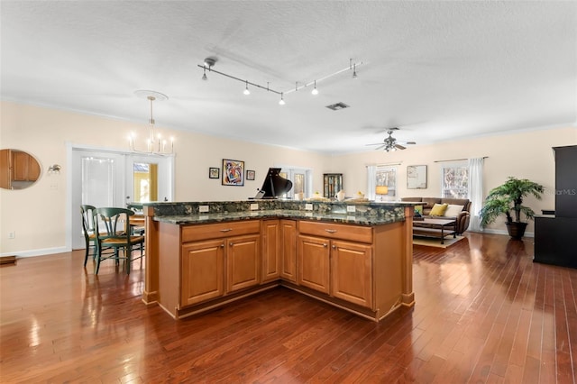 kitchen with a kitchen island, dark stone counters, dark hardwood / wood-style floors, and hanging light fixtures