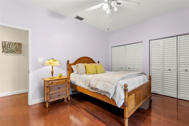 bedroom featuring dark hardwood / wood-style flooring, ceiling fan, and multiple closets