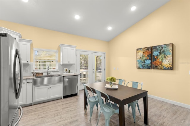 dining space featuring vaulted ceiling, sink, light wood-type flooring, and french doors