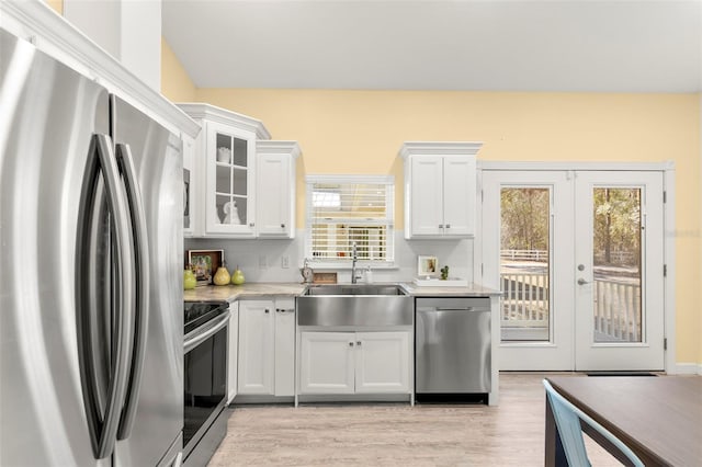 kitchen featuring sink, appliances with stainless steel finishes, light hardwood / wood-style floors, white cabinets, and french doors