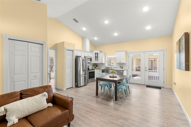 dining room featuring light hardwood / wood-style flooring, high vaulted ceiling, and french doors