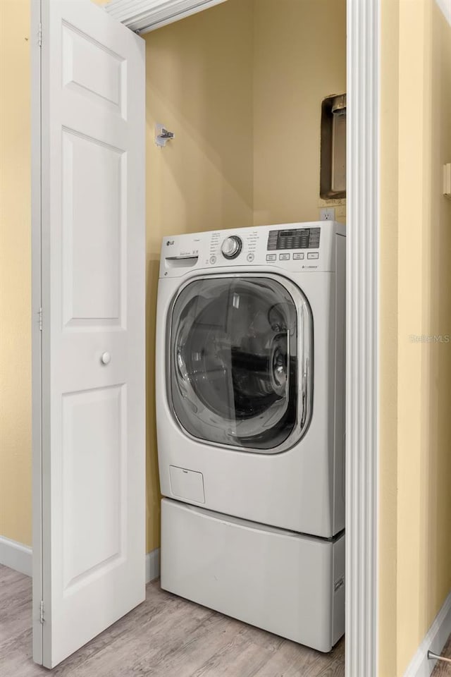 laundry area featuring washer / clothes dryer and light hardwood / wood-style floors