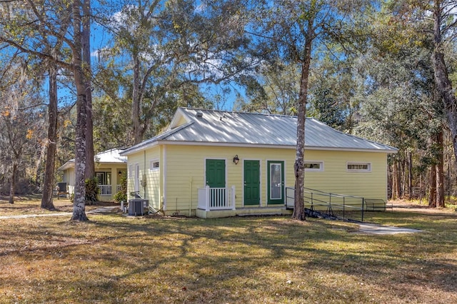 rear view of house with central AC unit and a yard