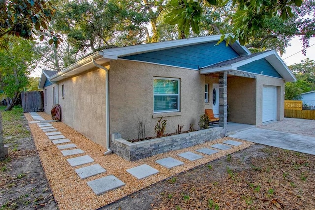 view of front facade with an attached garage, driveway, fence, and stucco siding