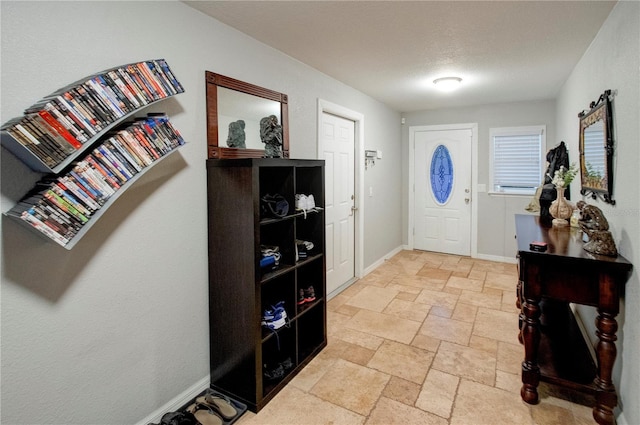 entrance foyer with stone tile floors, baseboards, and a textured ceiling