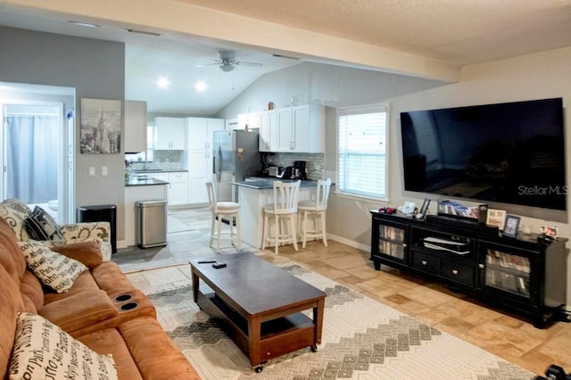 living area with a ceiling fan, lofted ceiling with beams, and baseboards