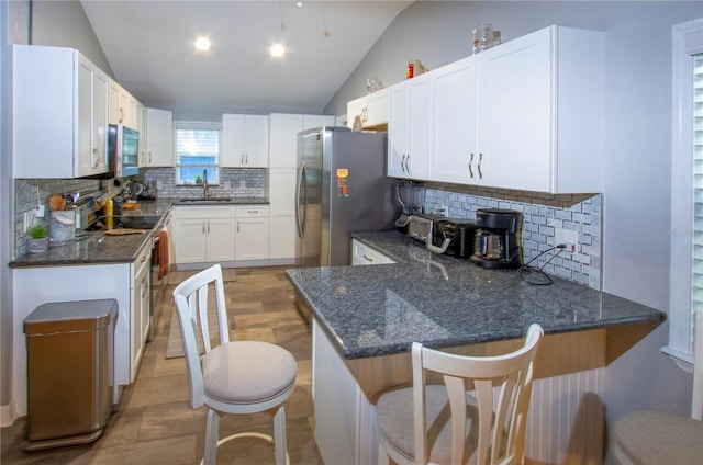 kitchen featuring a peninsula, a breakfast bar area, white cabinets, and a sink