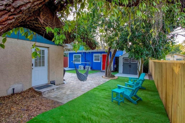 view of yard with a patio area, a fenced backyard, an outdoor structure, and a shed