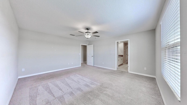 unfurnished room featuring ceiling fan, light carpet, and a textured ceiling