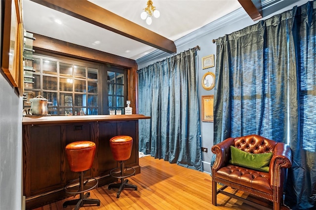 bar featuring beamed ceiling, ornamental molding, and hardwood / wood-style floors