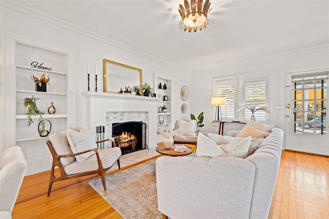 living room with crown molding, built in features, and light hardwood / wood-style floors