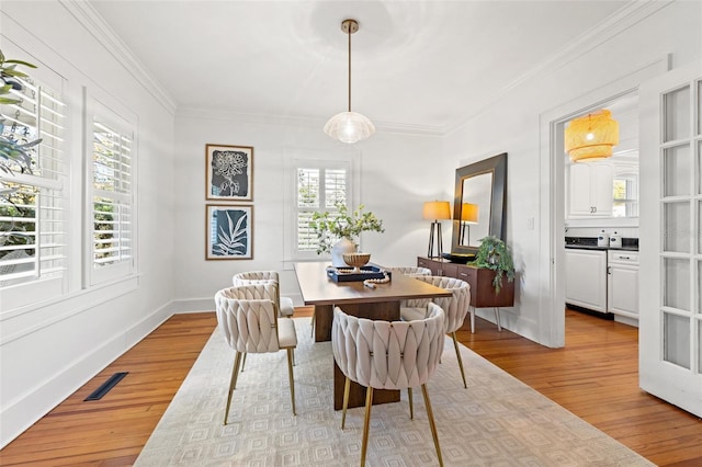 dining space with crown molding and light hardwood / wood-style flooring