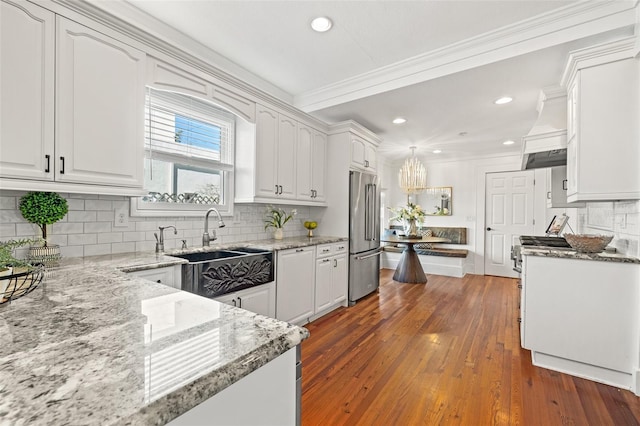 kitchen with white cabinetry, stainless steel appliances, decorative light fixtures, and light stone countertops