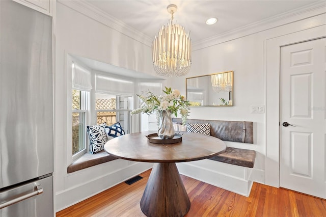 dining room featuring crown molding, hardwood / wood-style floors, a notable chandelier, and breakfast area