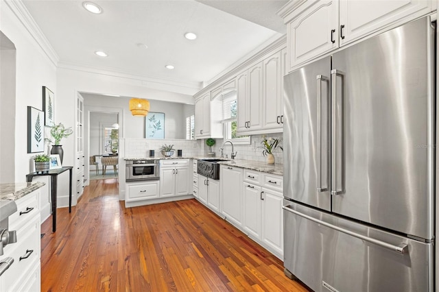 kitchen featuring light stone counters, high quality fridge, white cabinetry, and sink