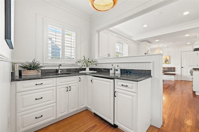 kitchen with white cabinetry, ornamental molding, light hardwood / wood-style flooring, and paneled dishwasher