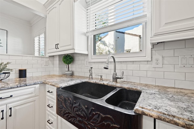 kitchen featuring light stone counters, sink, and white cabinets