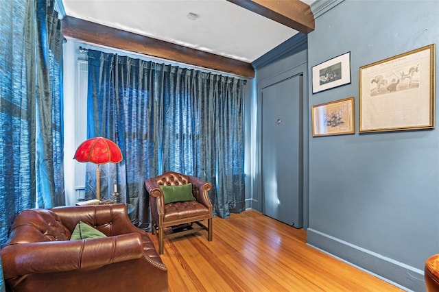 living area featuring wood-type flooring and beam ceiling