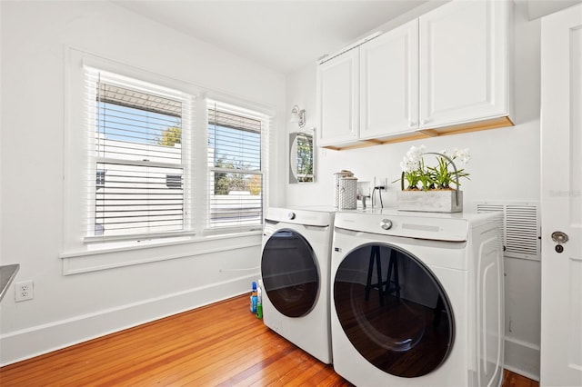 laundry room with cabinets, washer and dryer, and light wood-type flooring