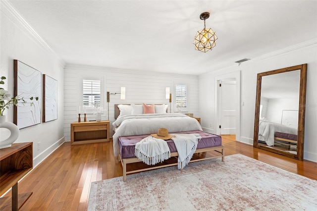 bedroom with ornamental molding and light hardwood / wood-style floors