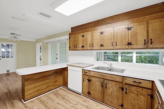 kitchen with light wood-type flooring, sink, white dishwasher, and kitchen peninsula