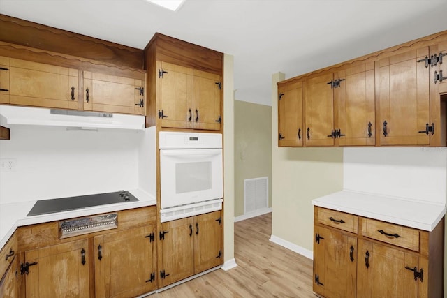 kitchen featuring black electric cooktop, light wood-type flooring, and white oven