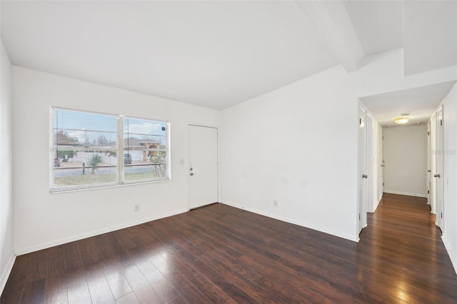 spare room featuring beam ceiling and dark wood-type flooring