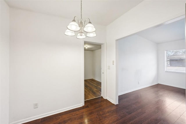 spare room featuring an inviting chandelier and dark hardwood / wood-style flooring