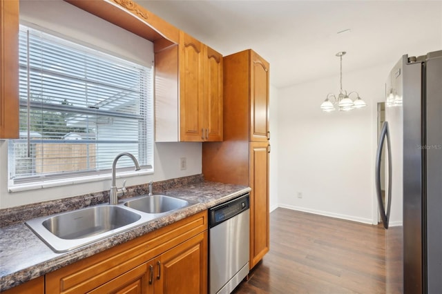 kitchen featuring sink, a chandelier, appliances with stainless steel finishes, dark hardwood / wood-style flooring, and pendant lighting