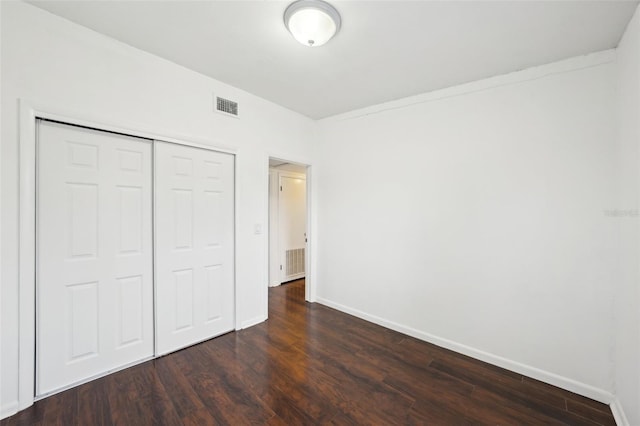 unfurnished bedroom featuring dark hardwood / wood-style flooring and a closet