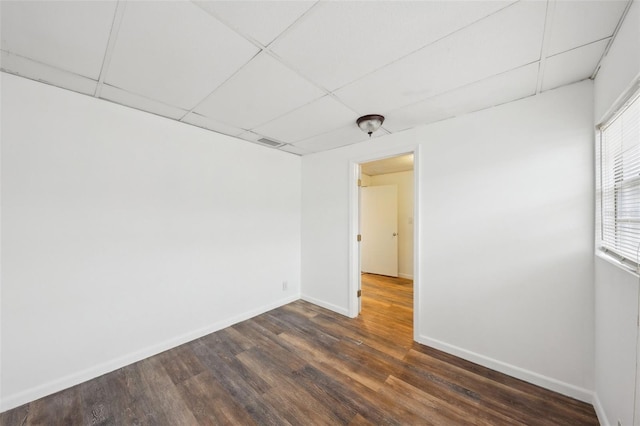 empty room featuring dark hardwood / wood-style flooring and a drop ceiling