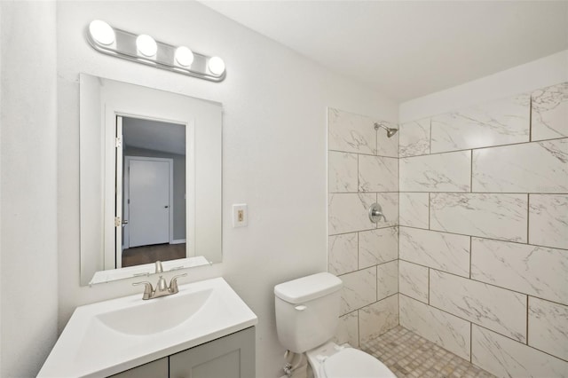 bathroom with vanity, toilet, and tiled shower