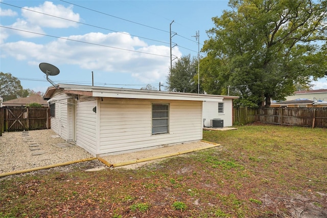 rear view of property featuring central AC and a lawn