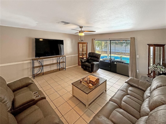 tiled living room with ceiling fan and a textured ceiling