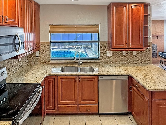 kitchen featuring sink, light stone counters, light tile patterned floors, stainless steel appliances, and decorative backsplash