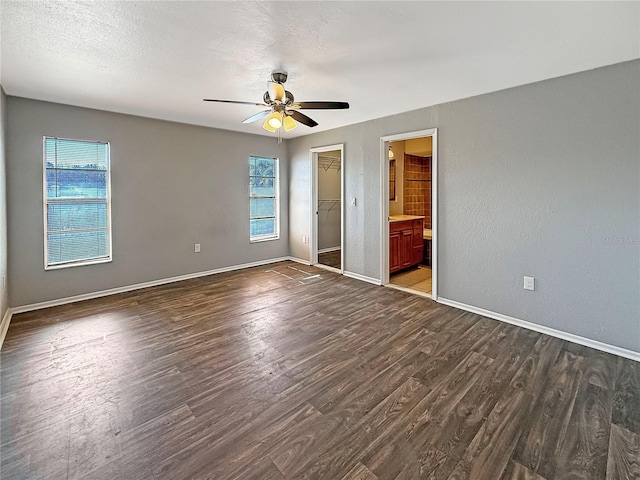 empty room featuring dark hardwood / wood-style flooring, ceiling fan, and a textured ceiling