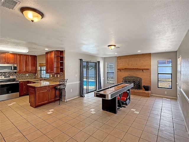 kitchen featuring stainless steel appliances, light tile patterned flooring, a center island, and decorative backsplash