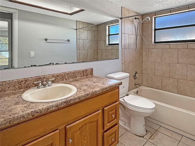 full bathroom featuring tiled shower / bath, vanity, toilet, tile patterned floors, and a textured ceiling