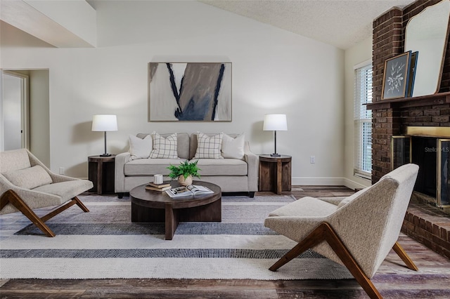 living room featuring lofted ceiling, hardwood / wood-style floors, a fireplace, and a textured ceiling