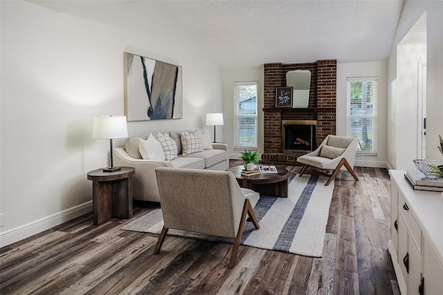 living room featuring a brick fireplace, dark hardwood / wood-style floors, and a textured ceiling