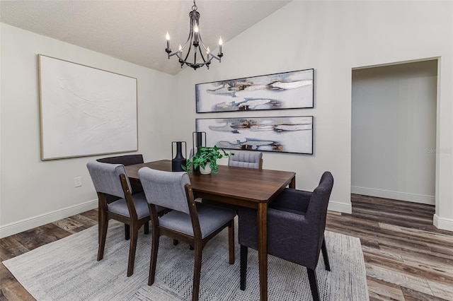 dining room featuring an inviting chandelier, hardwood / wood-style flooring, vaulted ceiling, and a textured ceiling