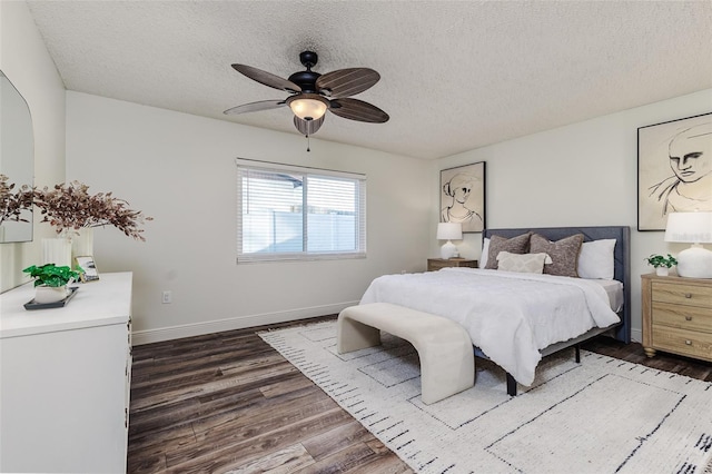 bedroom with ceiling fan, dark hardwood / wood-style flooring, and a textured ceiling