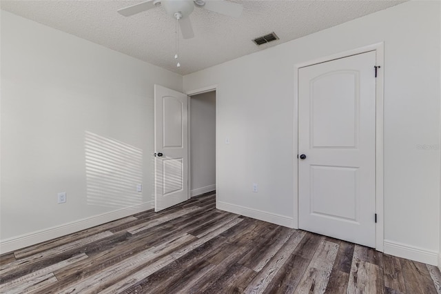 unfurnished bedroom featuring dark hardwood / wood-style flooring, a textured ceiling, ceiling fan, and a closet