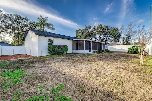 back of house with a lawn and a sunroom