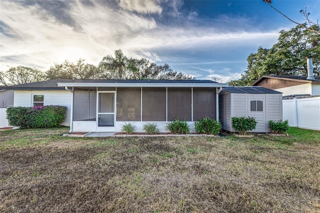 back of property featuring a yard, a sunroom, and a storage unit