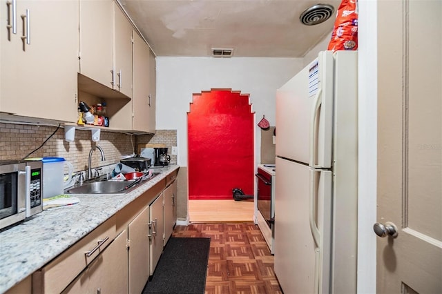 kitchen with dark parquet flooring, sink, white fridge, decorative backsplash, and stove