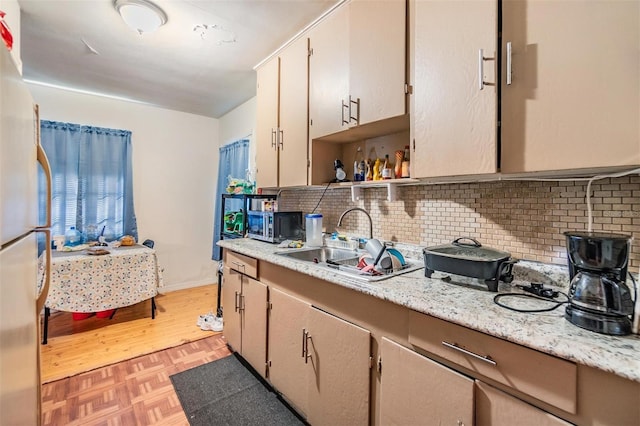 kitchen featuring tasteful backsplash, light stone countertops, sink, and light parquet floors