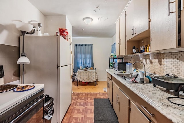 kitchen with sink, hanging light fixtures, electric range oven, light stone countertops, and backsplash