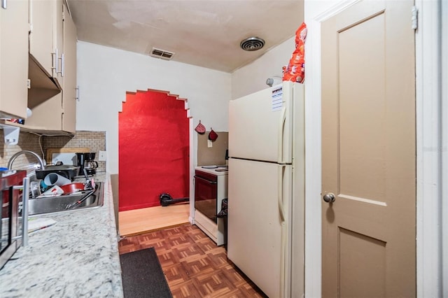 kitchen featuring sink, white appliances, white cabinetry, dark parquet flooring, and decorative backsplash